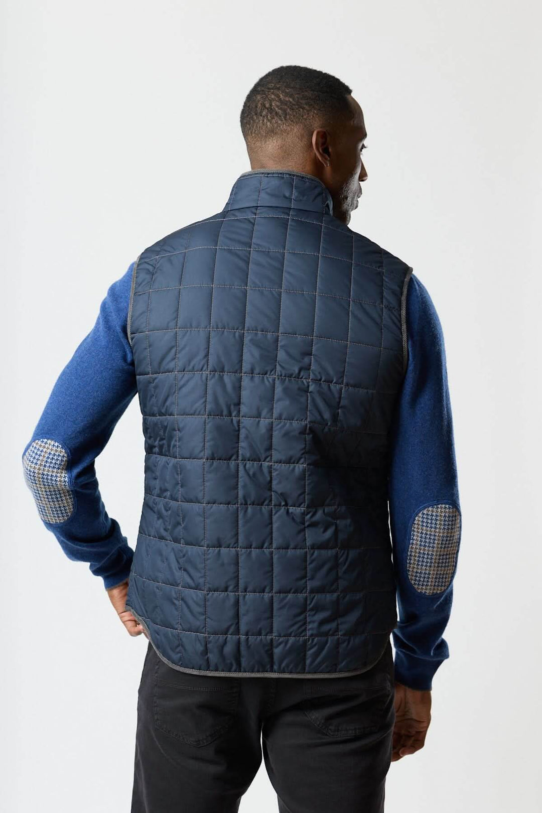 Homme portant une veste sans manches matelassée avec détails en velours côtelé vue de dos, mettant en valeur son design élégant.