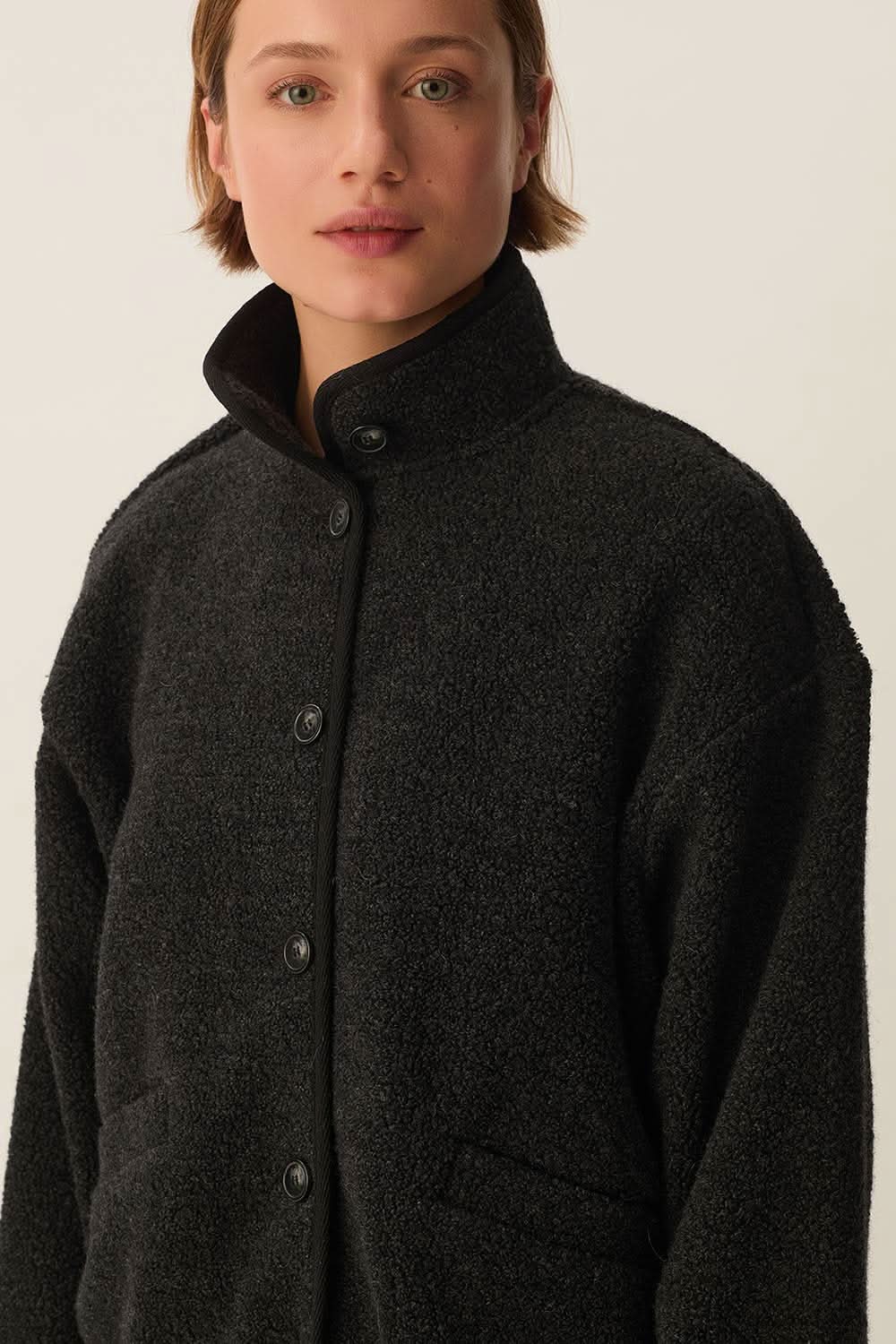 Veste Zlavina boutonnée en laine bouclée avec col montant, vue de face sur mannequin. Décris moi le produit en français.