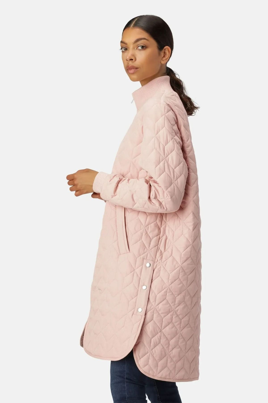 Femme portant un manteau matelassé long à col montant rose avec motifs géométriques, idéal pour un look urbain élégant et moderne.
