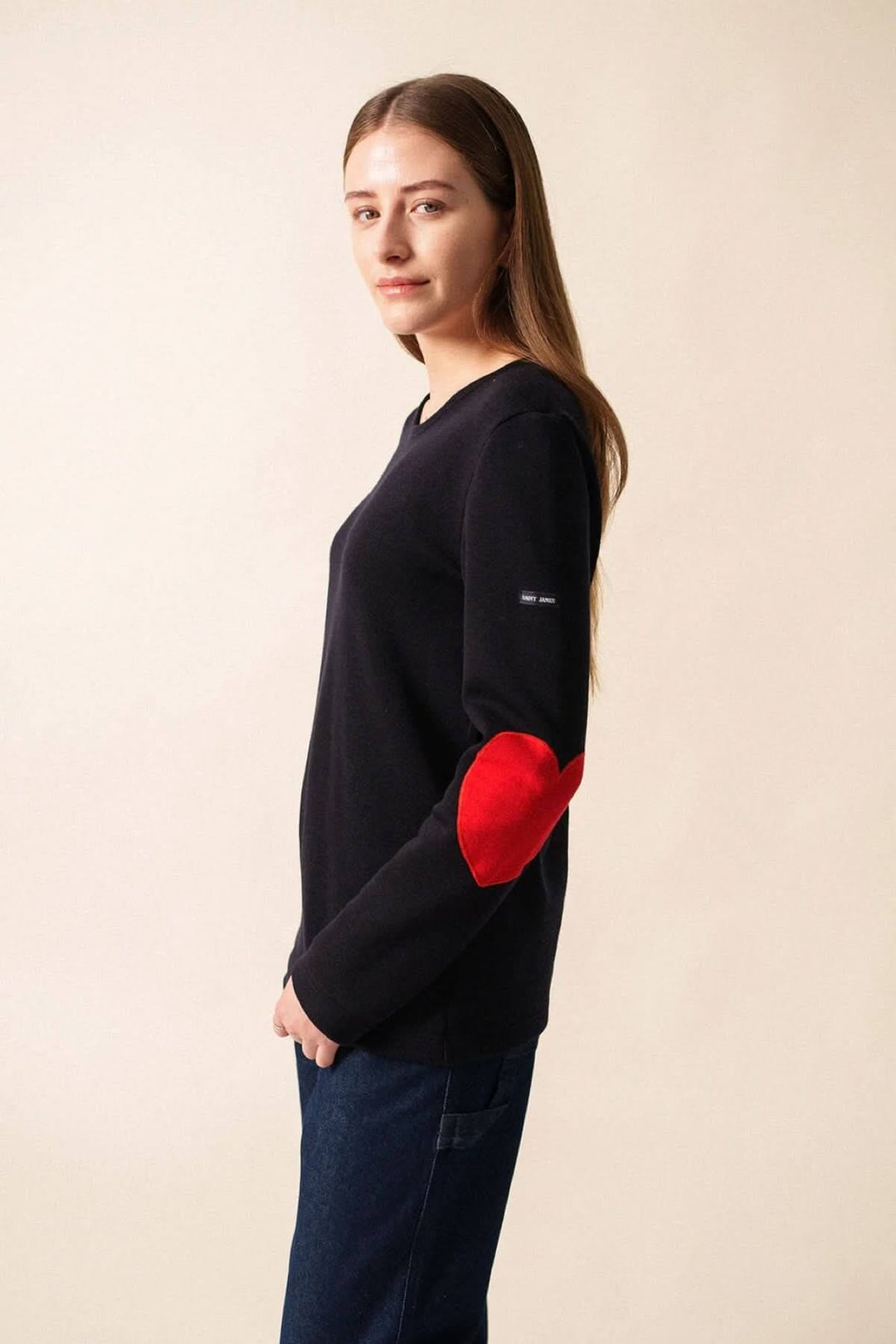 Chandail Vaujany à encolure ronde, avec coudes en cœur rouge, style moderne et confortable, porté avec un jean.