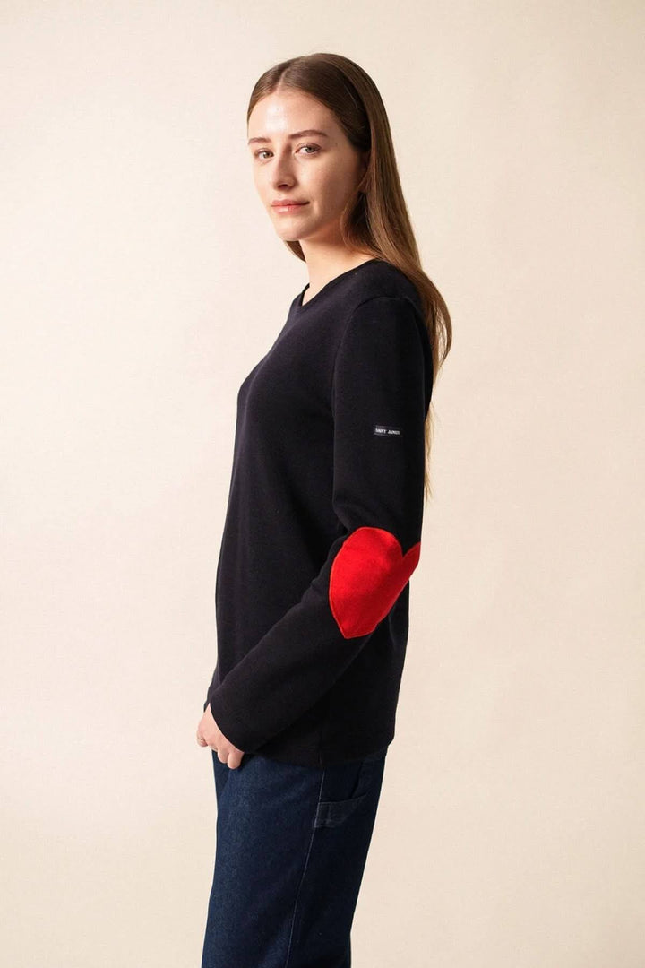 Chandail Vaujany à encolure ronde, avec coudes en cœur rouge, style moderne et confortable, porté avec un jean.