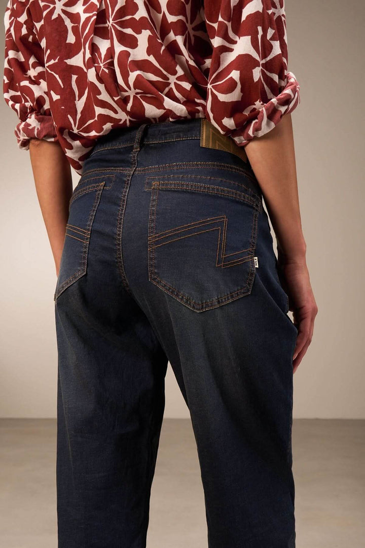 Jean à coupe décontractée en denim foncé, avec revers apparents et détails de couture visibles.