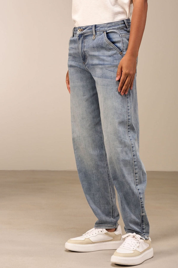 Jean à coupe droite délavé, taille mi-haute, porté avec des baskets blanches pour un look décontracté.