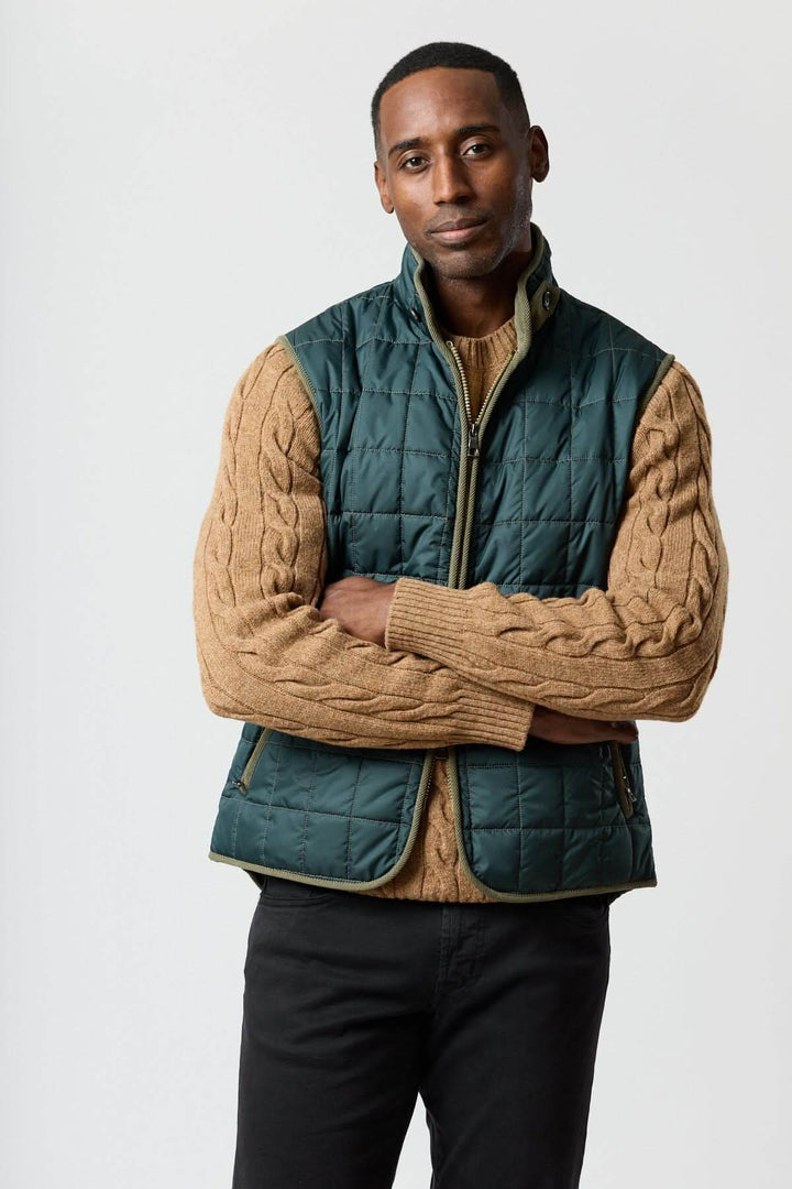 Veste sans manches matelassée avec détails en velours côtelé portée avec un pull marron, style élégant et pratique.