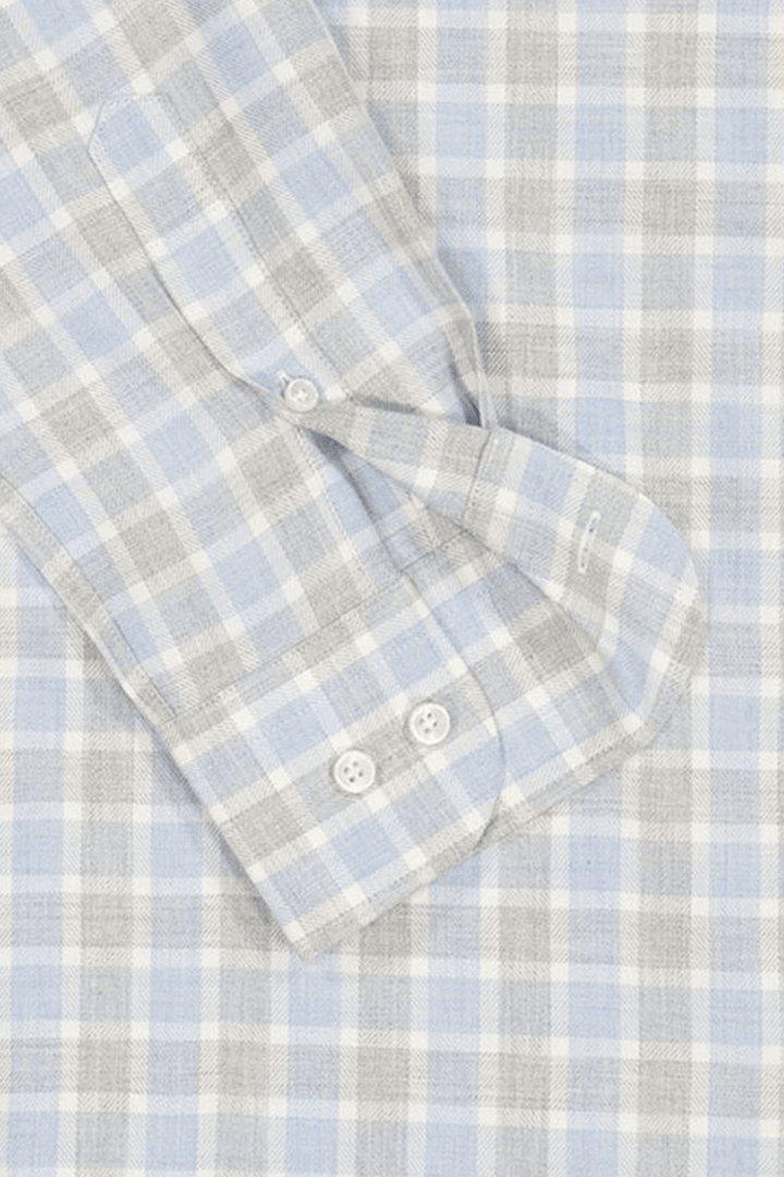 Chemise en flanelle à carreaux bleu pâle et gris avec col boutonné et détails modernes.
