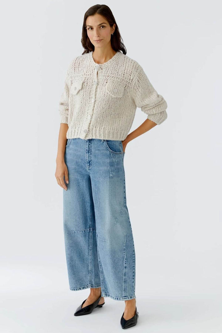 Femme portant une veste en tricot épais à boutons bijoux, chic et cosy, idéale pour tenues d'automne et d'hiver.