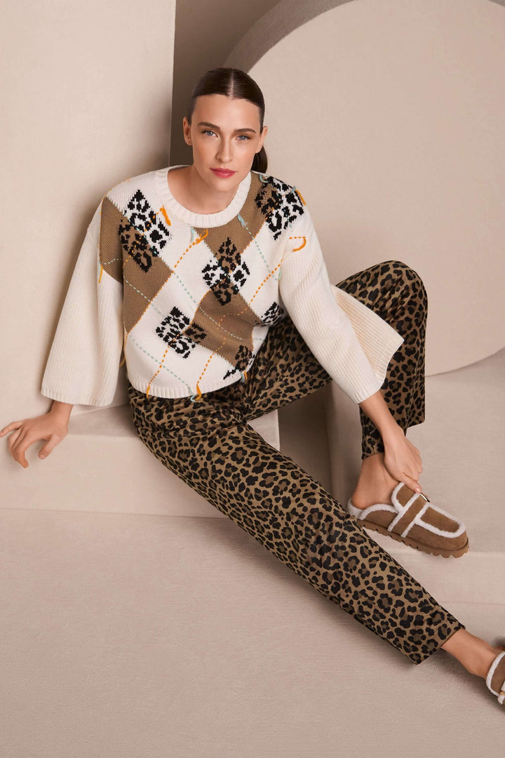 Femme portant un chandail à motif losanges et accents léopard avec un pantalon léopard, style moderne et confortable.