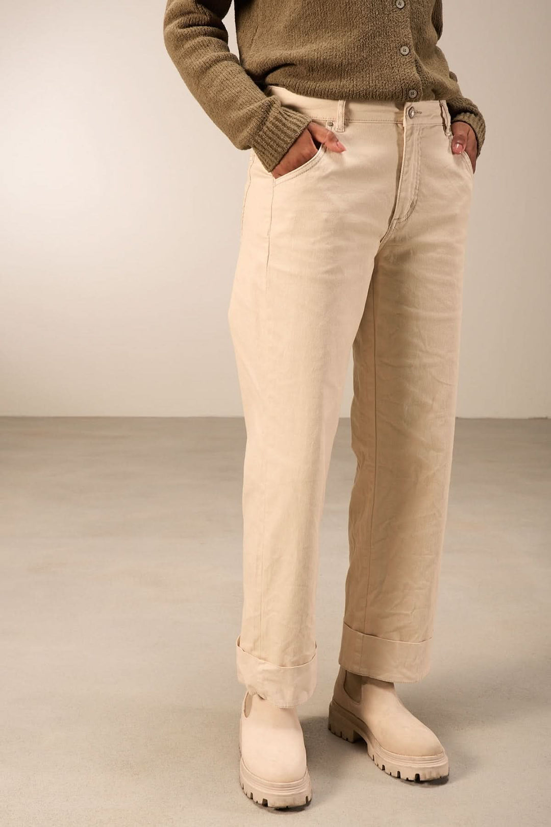Pantalon droit beige avec taille mi-haute, poches et coupe décontractée, porté avec chandail et bottines.