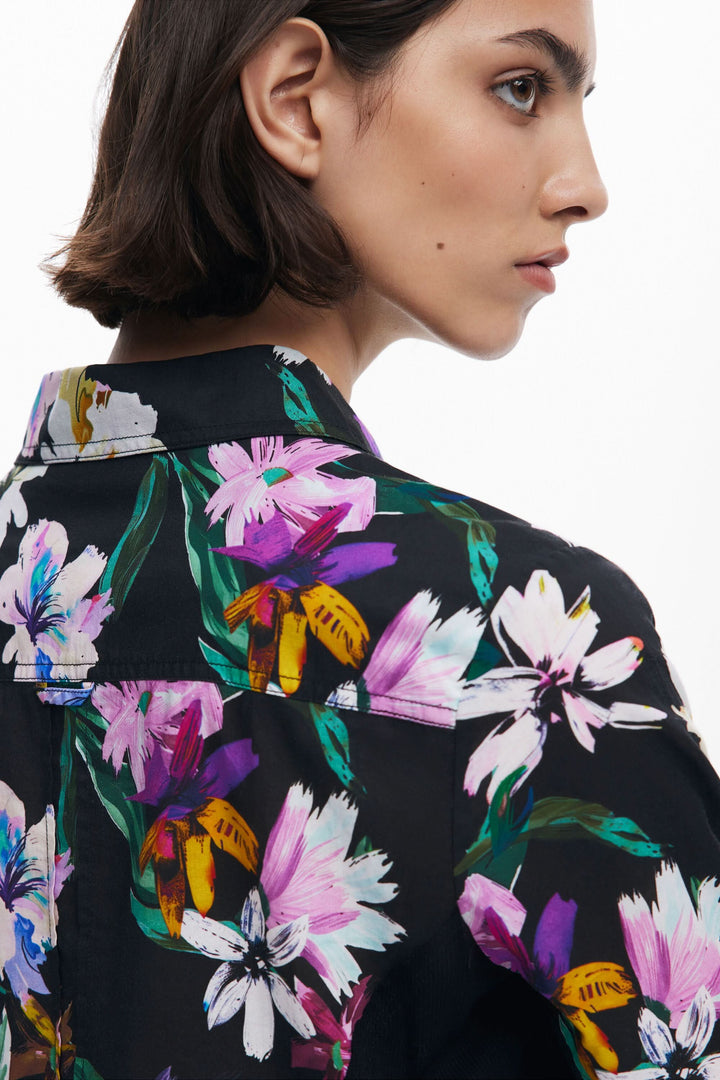 Chemise à fleurs avec un col classique, en tissu léger et couleurs éclatantes, modelée sur un fond noir.