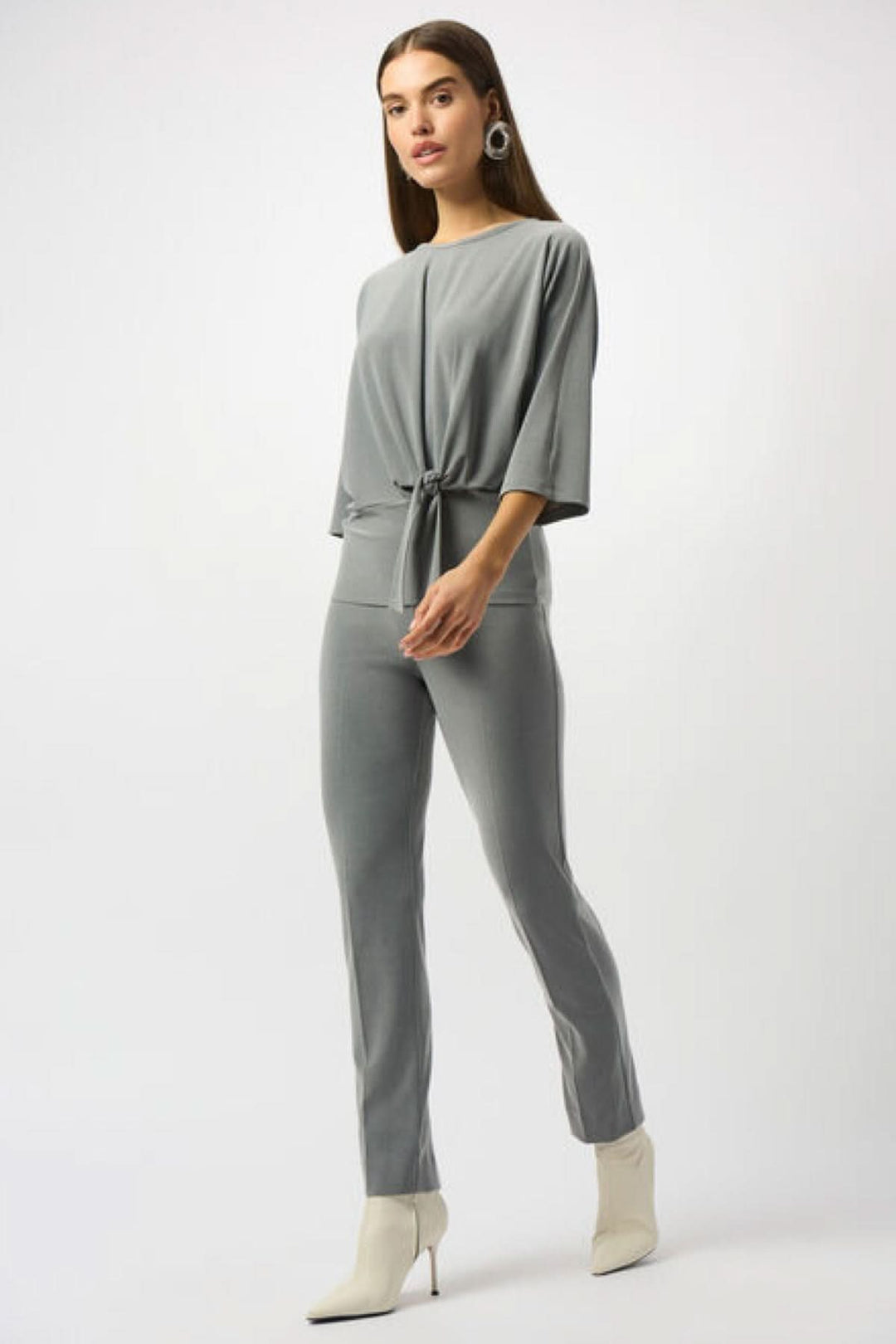 Femme en pantalon classique gris mélangé, coupe ajustée, taille élastique et le haut noué, style chic décontracté.