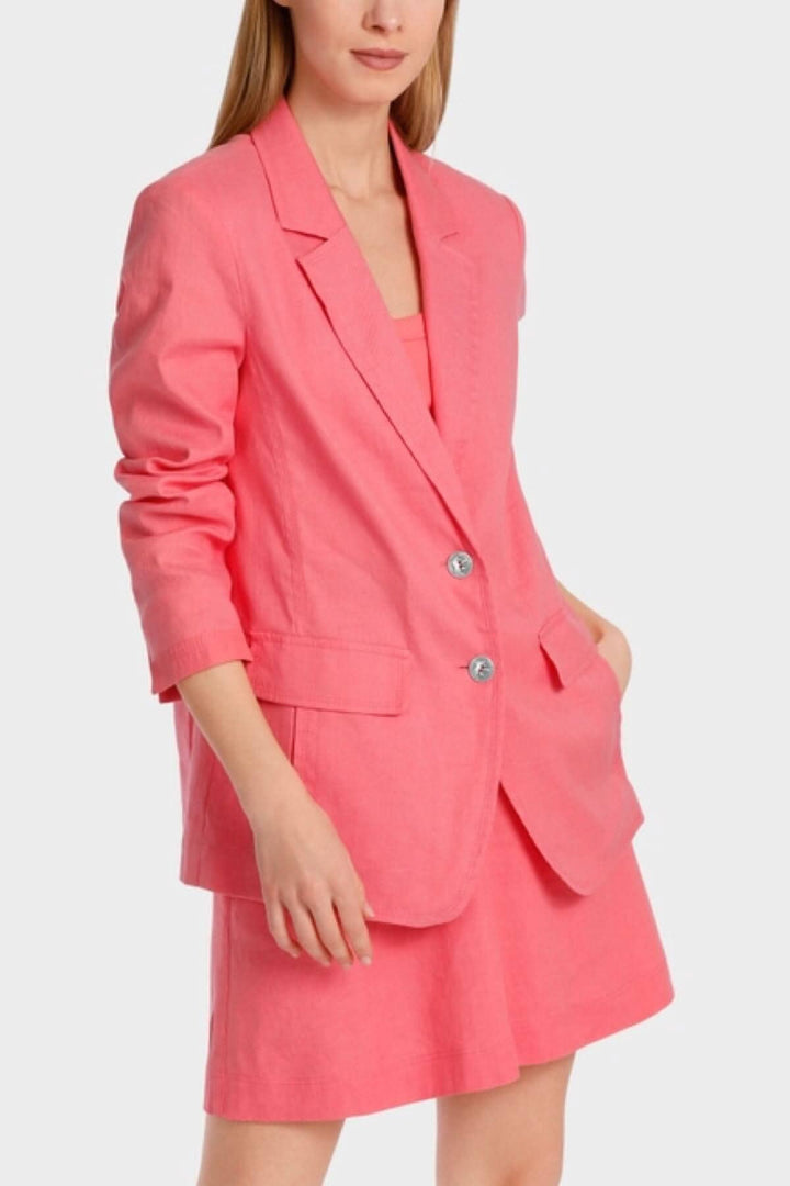 Femme portant un blazer rose vif sur une jupe assortie, style décontracté et élégant, parfait pour l'été.