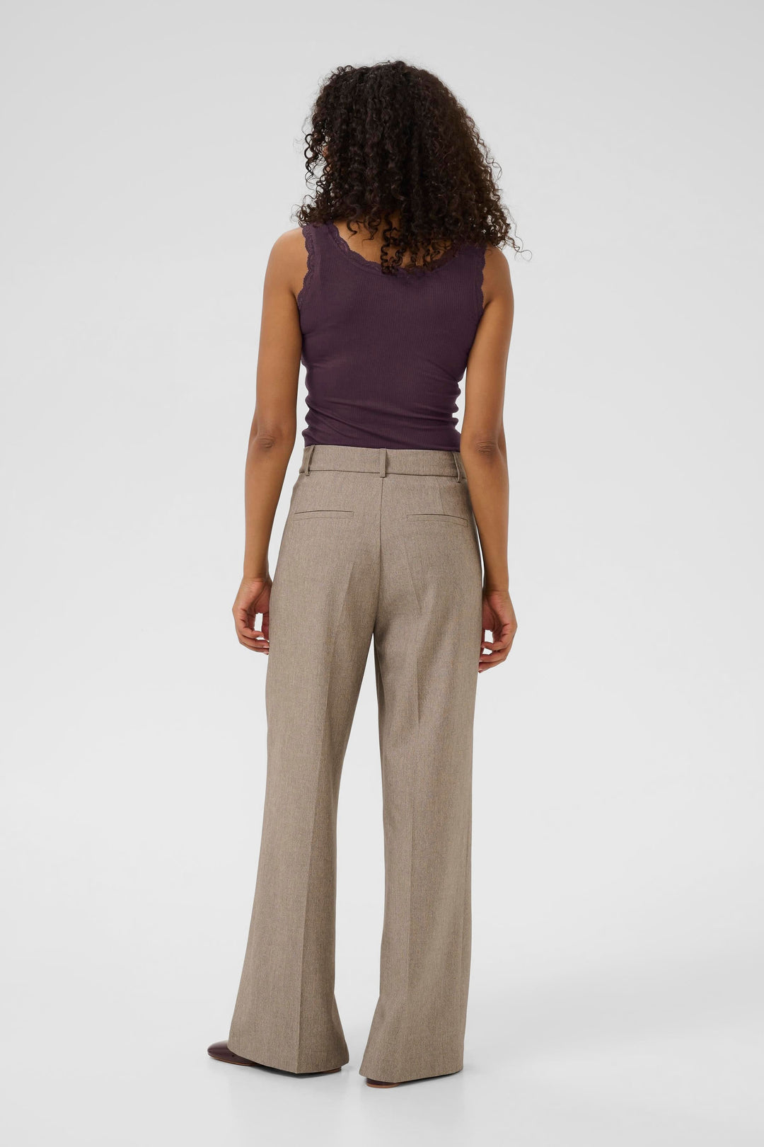 Femme vue de dos portant une camisole côtelée violette avec un pantalon beige, style confortable et raffiné.