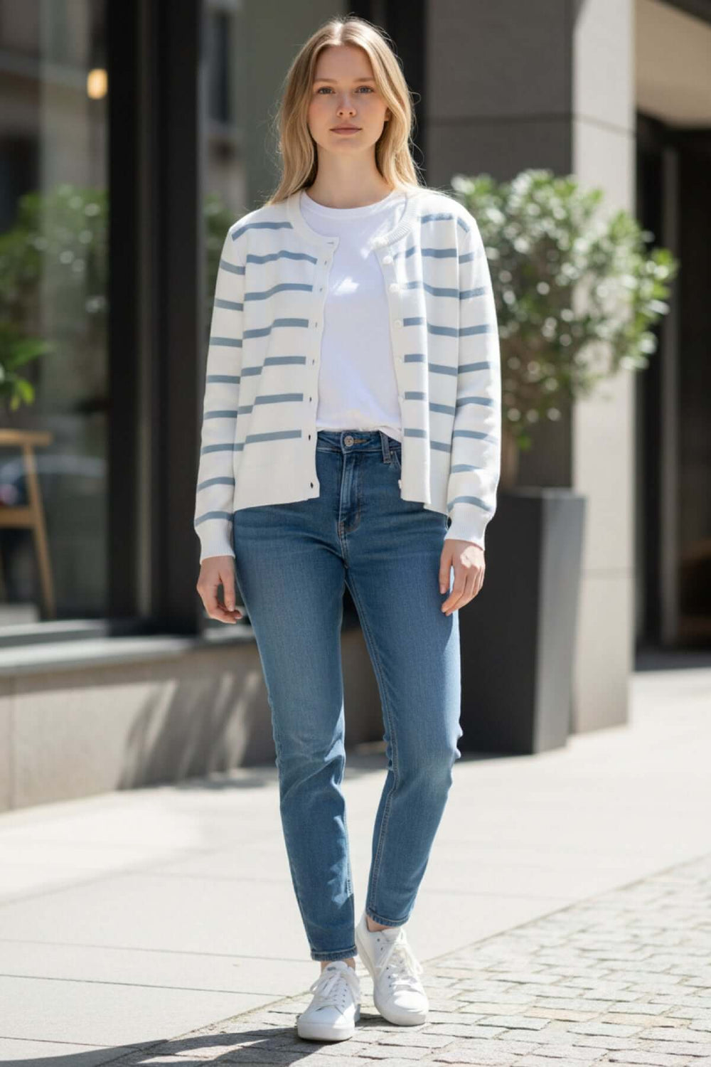 Femme portant un cardigan à rayures boutonné PERPIGNAN, style décontracté avec jeans et baskets blanches, col arrondi.
