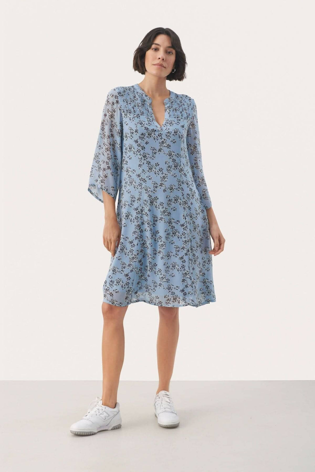 Robe fleurie Elka, légère et élégante, idéale pour toutes les occasions, portée avec des baskets blanches.