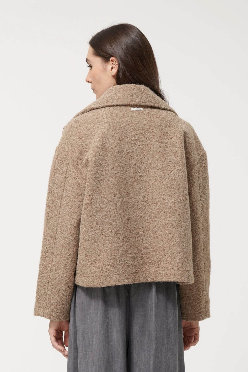 Vue arrière de la veste courte à double boutonnage en matière texturée, coupe moderne et col tailleur oversize, modèle mi-saison.