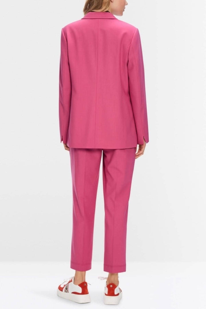 Vue arrière d'un veston à coupe étroite rose, assorti à un pantalon, porté avec des sneakers blanches et rouges.