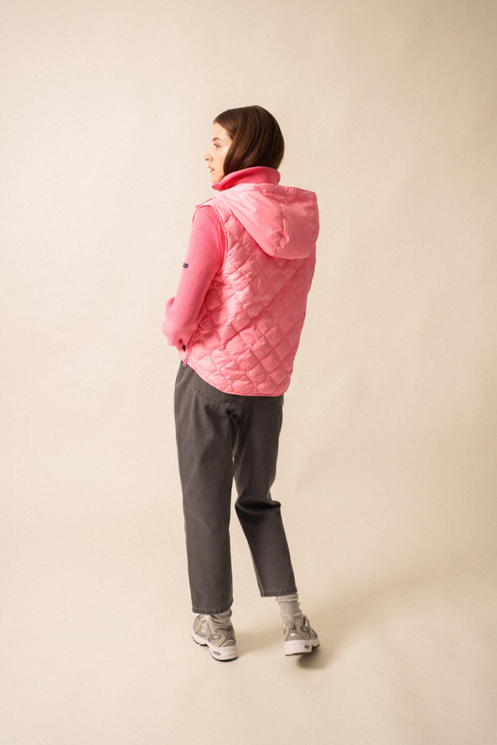 Vue arrière d'une femme en doudoune sans manche rose, associée à un pull, pour un look urbain et sportif.