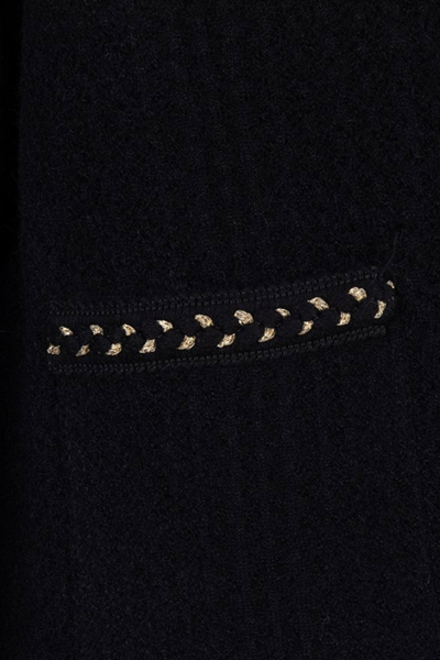 Détail d'un cardigan chic en noir avec motif de couture contrastant sur la poche.