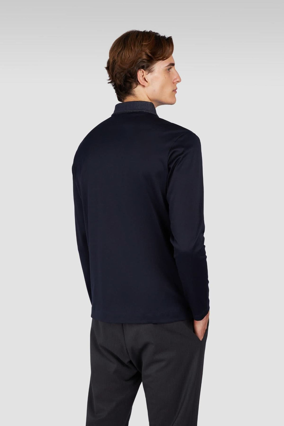 Homme portant un polo manches longues en coton noir vu de dos avec col contrastant.