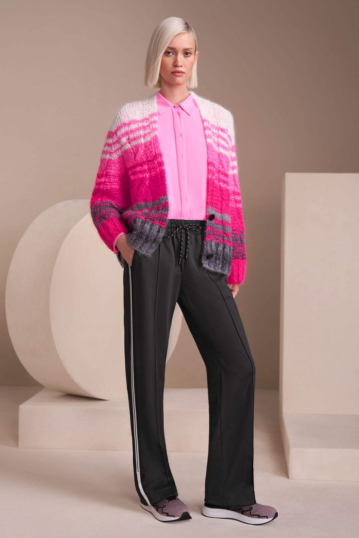 Femme portant un pantalon Washington sportwear noir avec une chemise rose et un cardigan coloré.