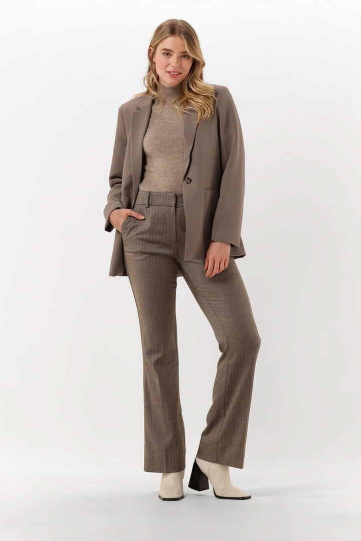 Femme portant un chandail col montant manches courtes — maille fine sous un blazer, look élégant et moderne.