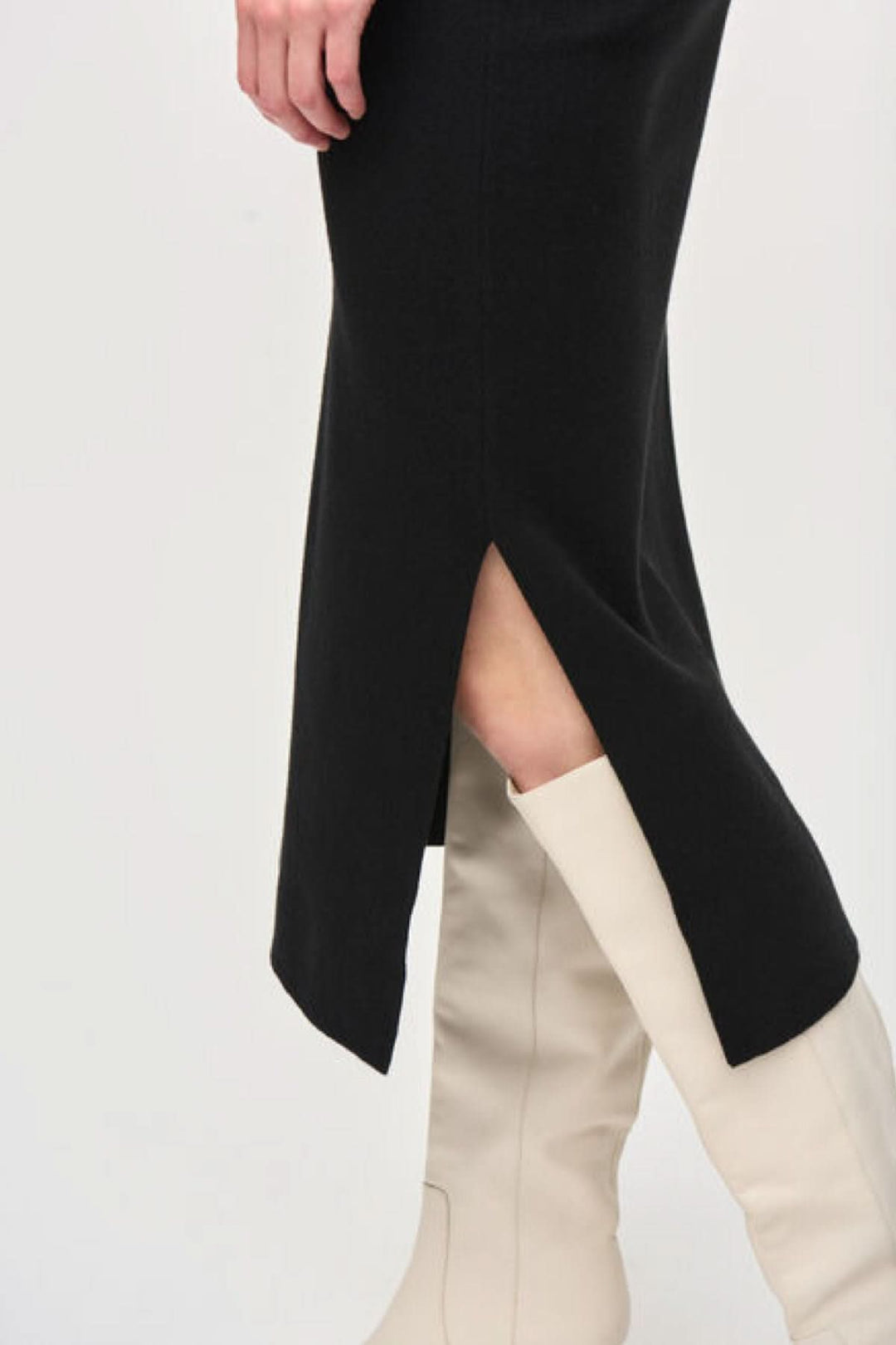 Jupe crayon noir en tricot avec fente latérale, portée avec des bottes blanches élégantes.