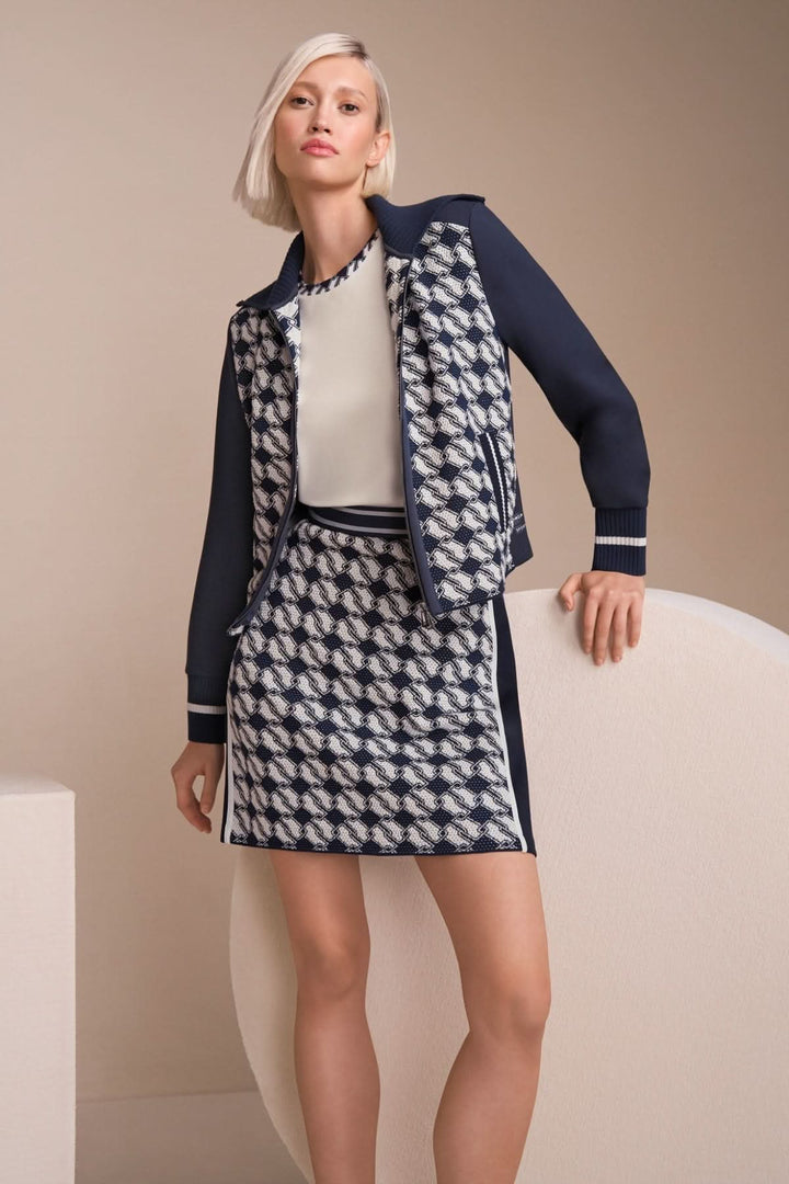 Femme en tenue élégante avec un blouson et une jupe à motifs géométriques, look moderne et chic.