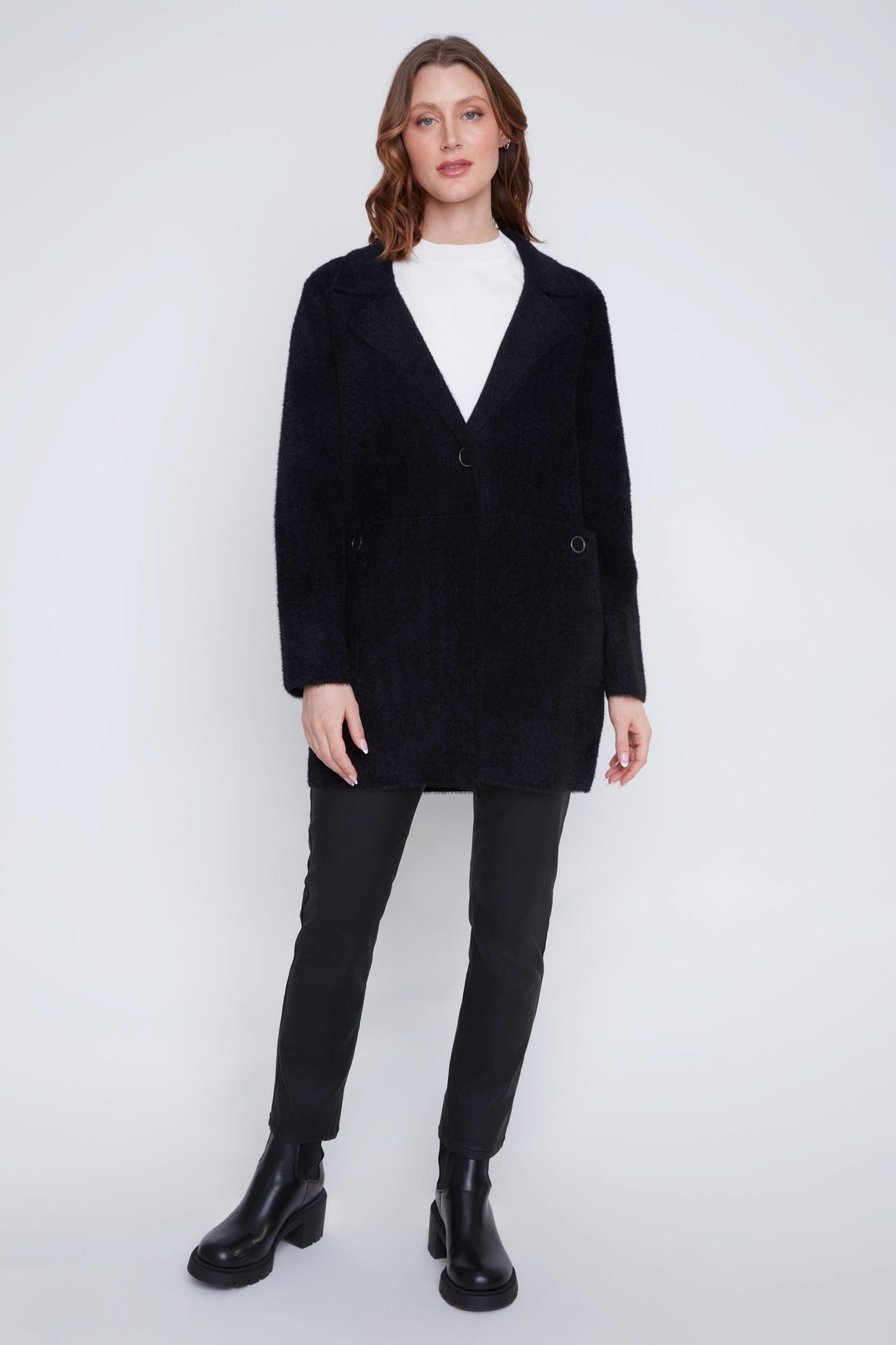 Manteau à poils courts noir avec col à revers, porté sur un pantalon ajusté et bottines, style élégant et confortable.