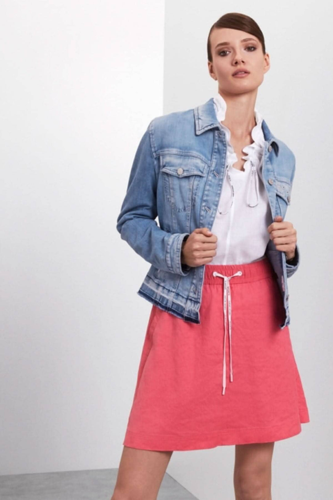 Femme portant une jupe courte rose et une veste en jean, style décontracté parfait pour l'été.