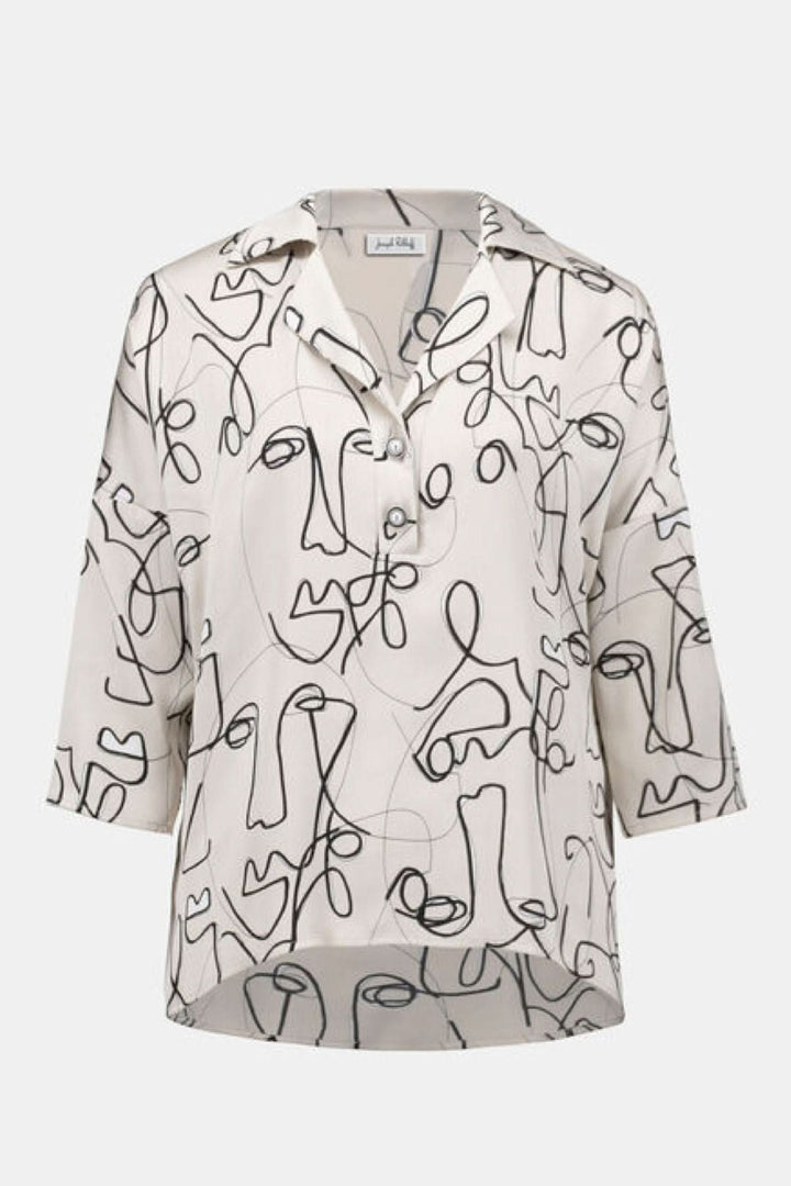 Blouse imprimée graphique avec motifs abstraits de visages, col chemise, manches mi-longues et ourlet arrière allongé.