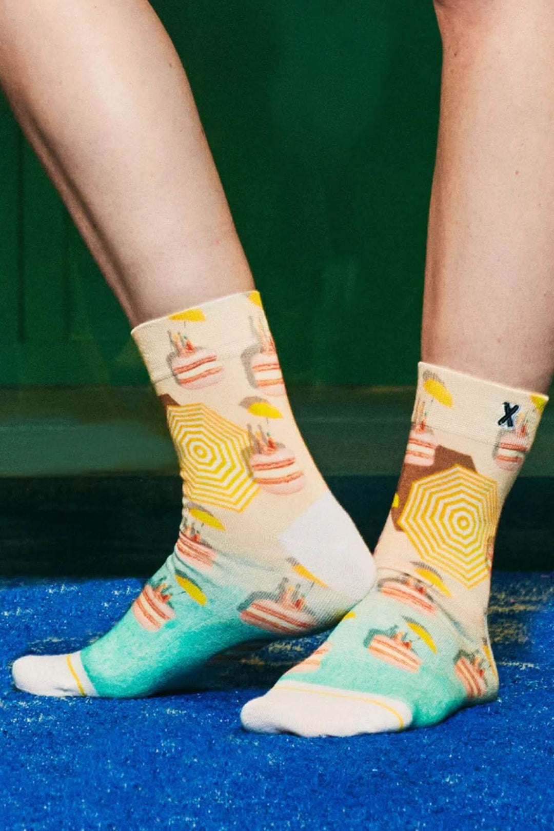 Chaussettes mi-hautes colorées avec imprimé macarons et parasols sur fond bleu.