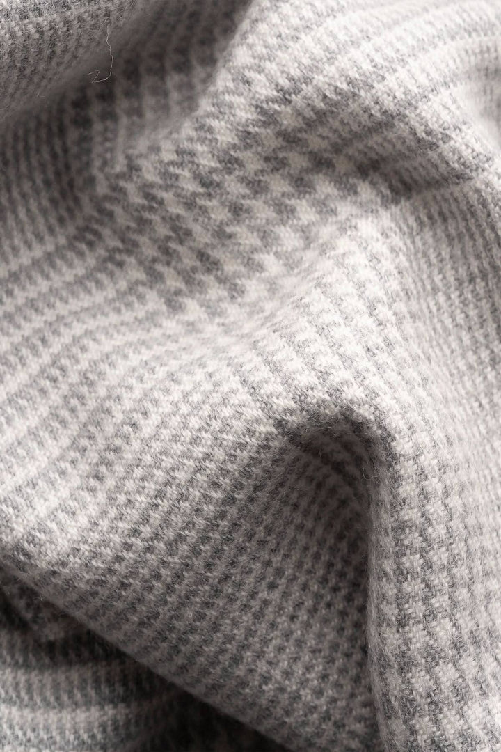 Foulard en laine à motif Prince de Galles en gris clair et blanc, texture douce et chaleureuse.