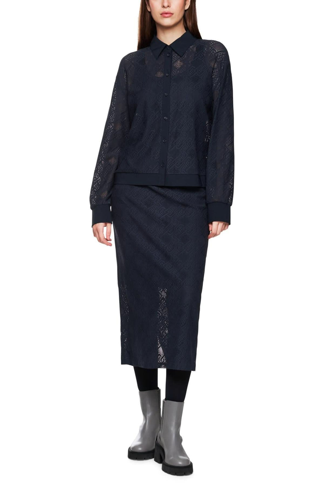 Femme portant une chemise en dentelle ajourée avec une jupe assortie, look décontracté et moderne.