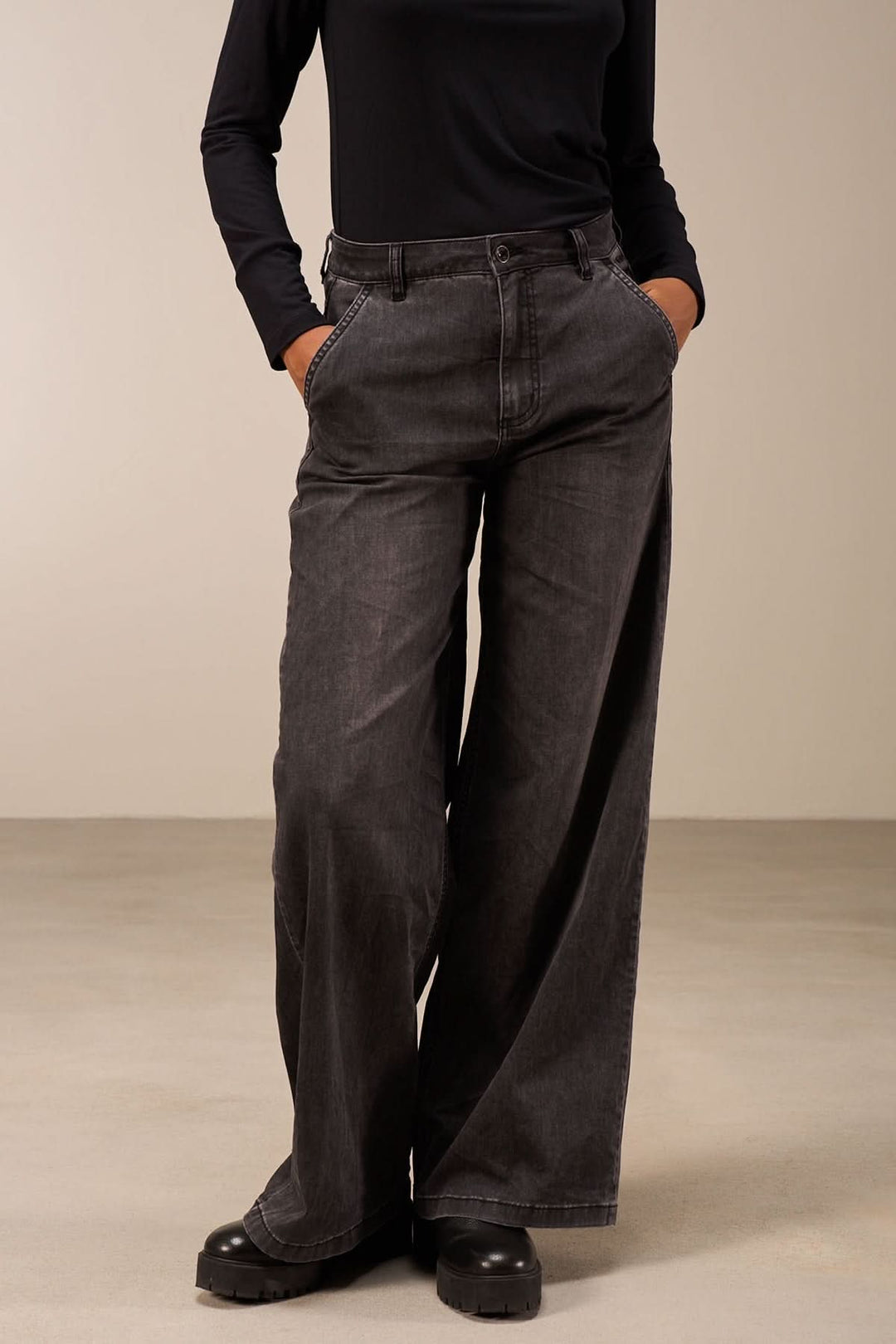 Jean coupe large noir avec taille mi-haute, jambes amples et poches, porté avec un haut ajusté.