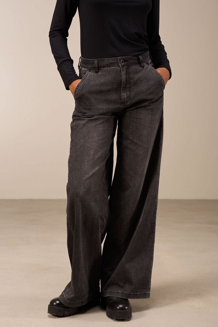 Jean coupe large noir avec taille mi-haute, jambes amples et poches, porté avec un haut ajusté.