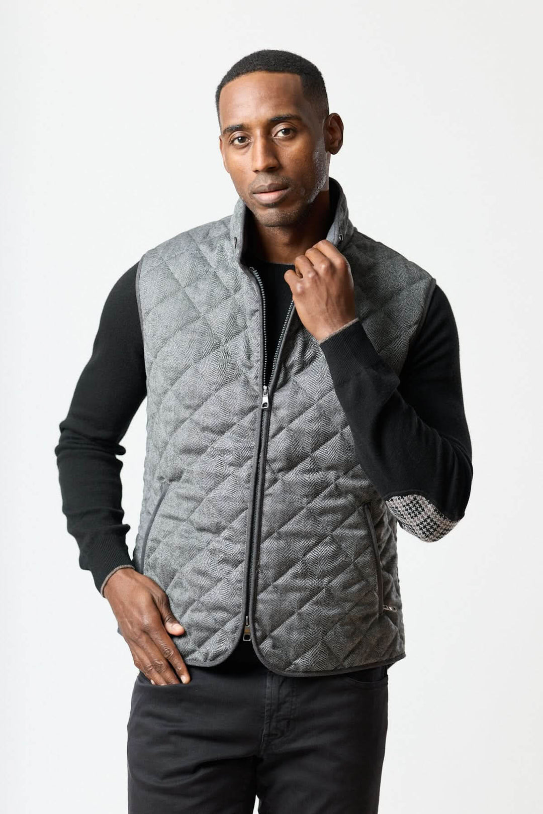 Homme portant une veste sans manches matelassée en laine à motif chevrons avec col montant, idéale pour un look élégant et urbain.