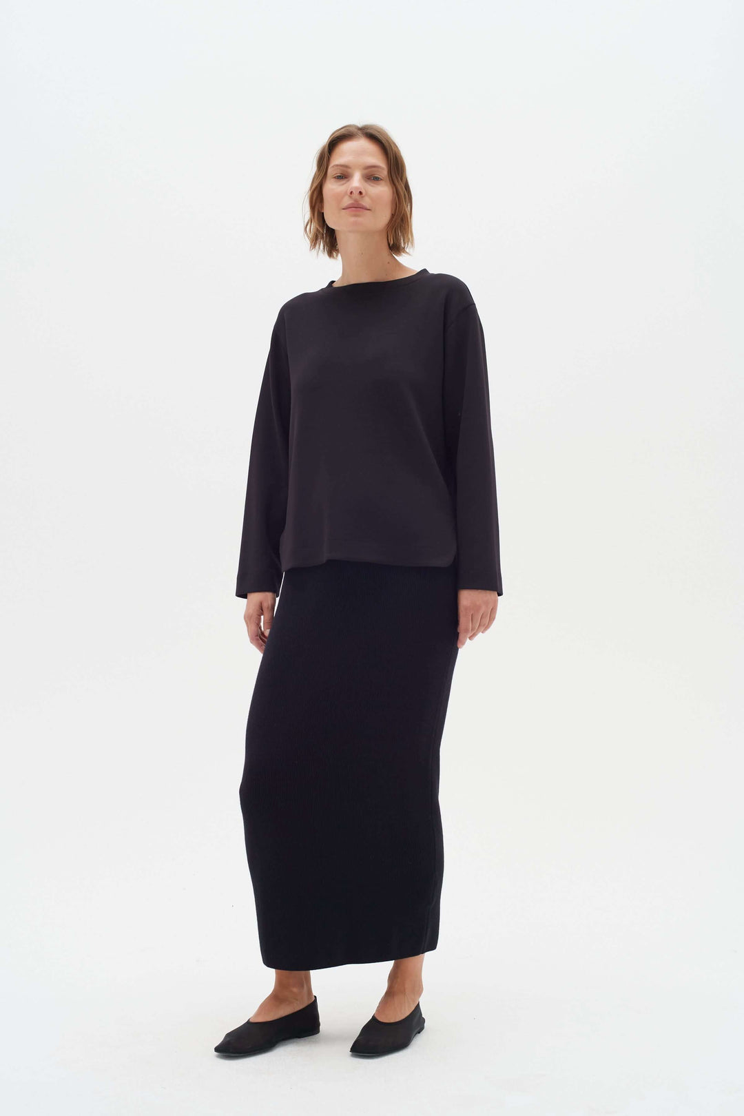 Chandail Gincent noir à manches longues avec jupe assortie, style élégant et minimaliste, col bateau.