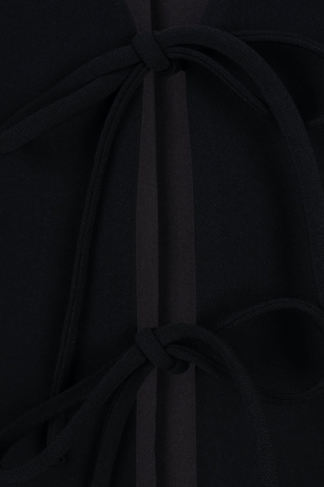 Détails de la veste sans manches avec liens à nouer sur un tissu noir élégant.