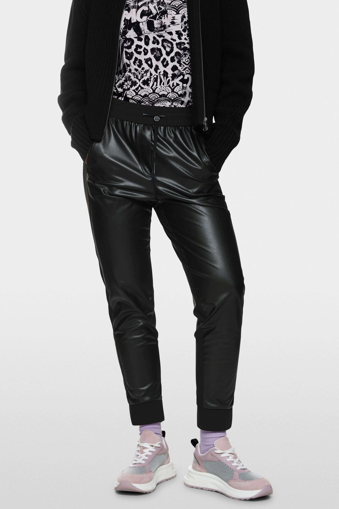 Pantalon habillé Rhodos en cuir, style sportswear moderne, porté avec baskets pour un look décontracté.