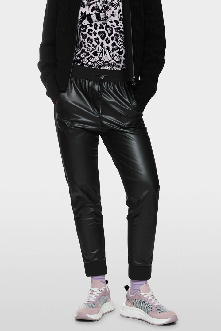 Pantalon habillé Rhodos en cuir, style sportswear moderne, porté avec baskets pour un look décontracté.