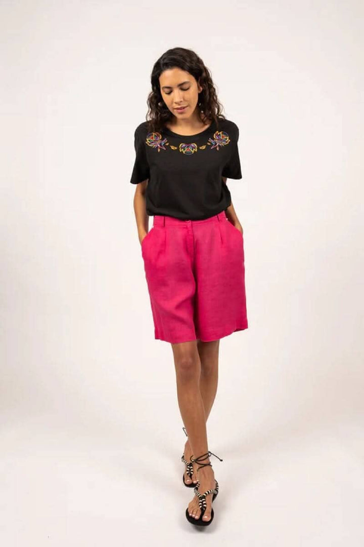 Femme portant un short Cécile rose et un haut noir, look chic et contemporain, idéal pour l'été.