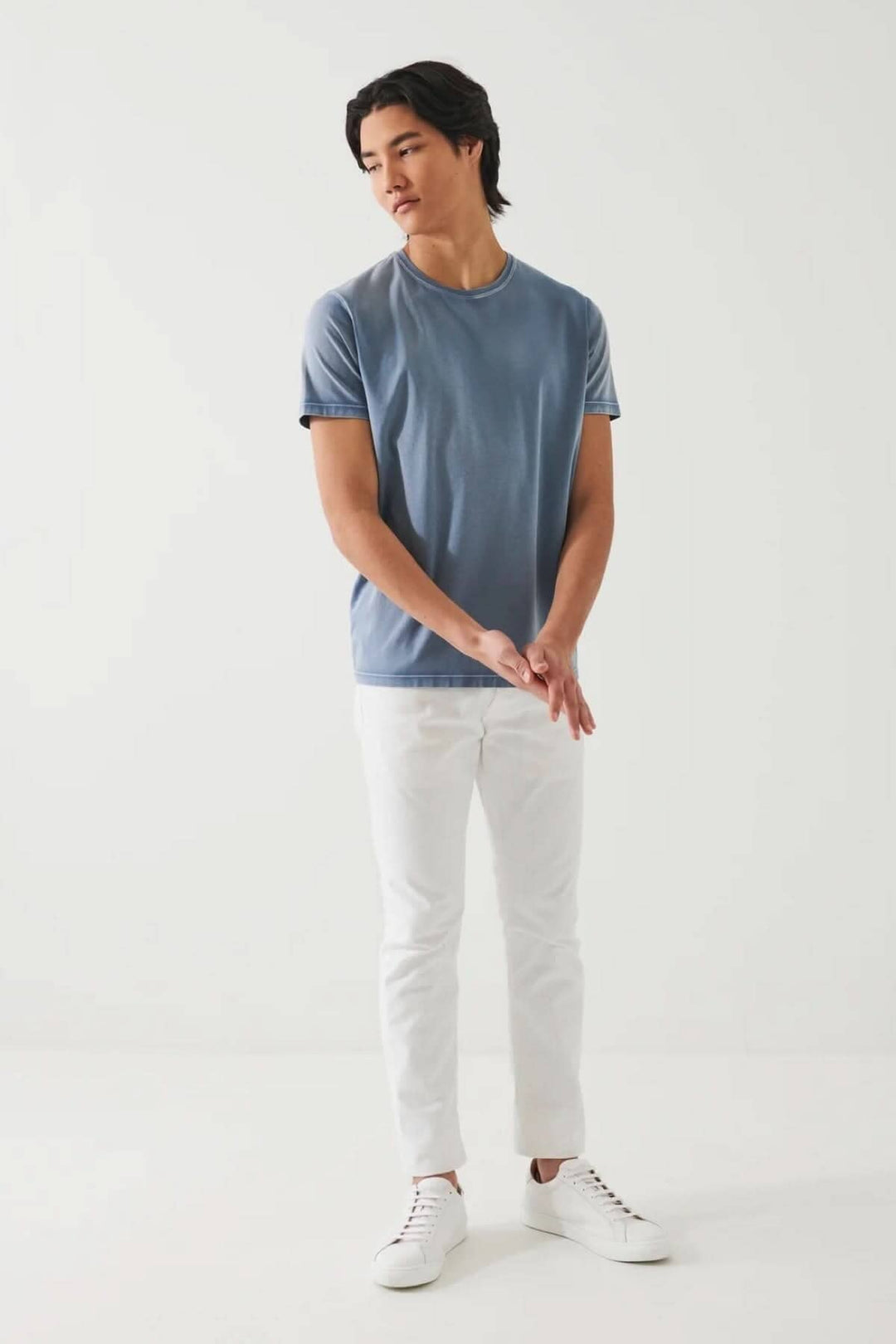 Homme portant un t-shirt stretch vintage wash bleu avec pantalon blanc, style décontracté élégant.