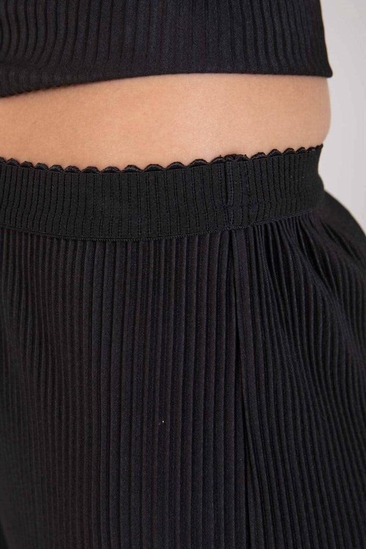 Détail de pantalon ample noir avec taille élastique et motif plissé, parfait pour un style chic et décontracté.