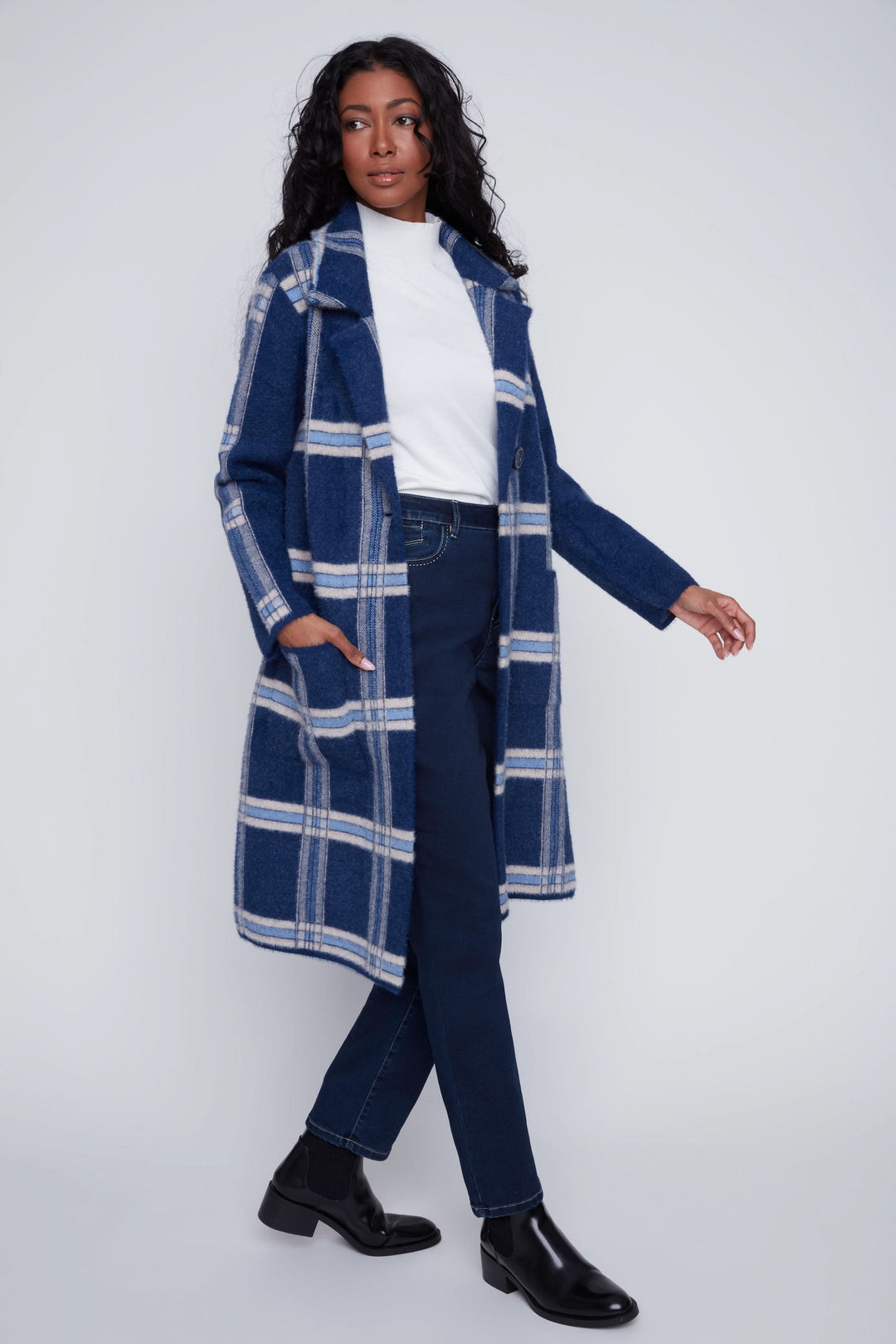 Manteau long à carreaux bleu marine, porté avec un t-shirt blanc et un pantalon ajusté pour un look chic et moderne.