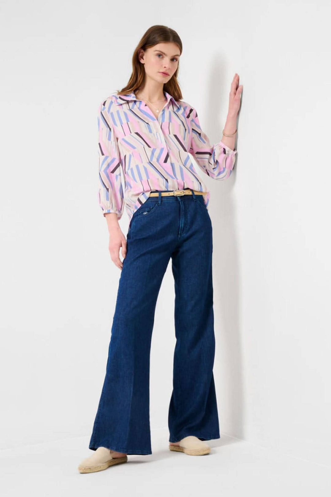 Femme portant un chemisier à motifs colorés et un jeans large MAINE avec ceinture, dans un cadre minimaliste.