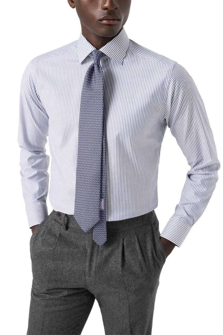 Chemise lignée élégante et intemporelle avec fines rayures bleu marine et col cutaway, portée sous costume.