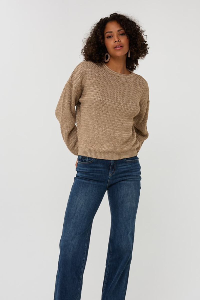 Chandail gaufré beige à manches longues, porté avec un jean évasé pour un look décontracté chic.