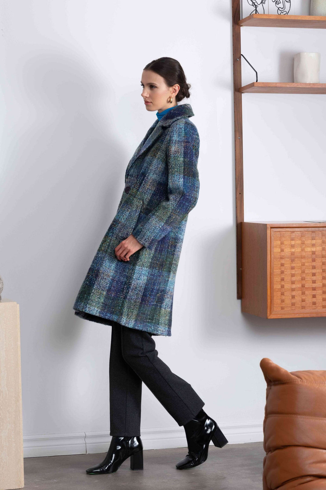 Manteau à carreaux mi-long avec un motif élégant en teintes profondes, porté avec un pantalon noir.