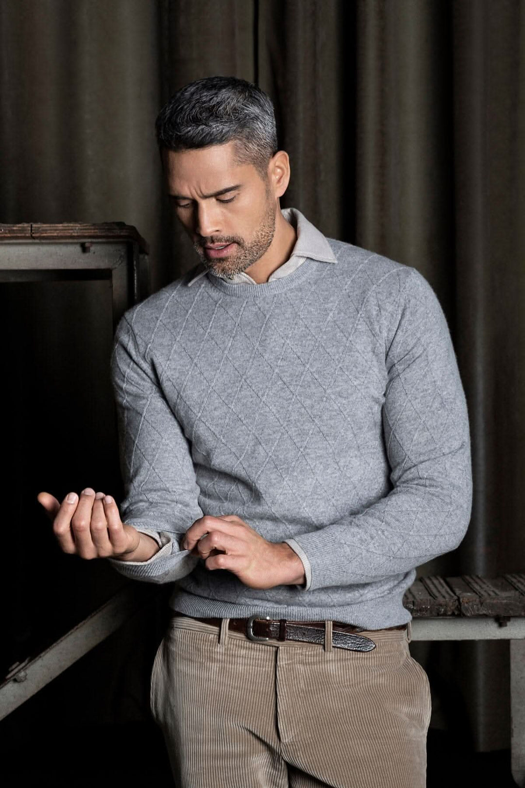 Chandail de cachemire texturé gris avec tricotage Harlequin, homme ajustant son poignet.