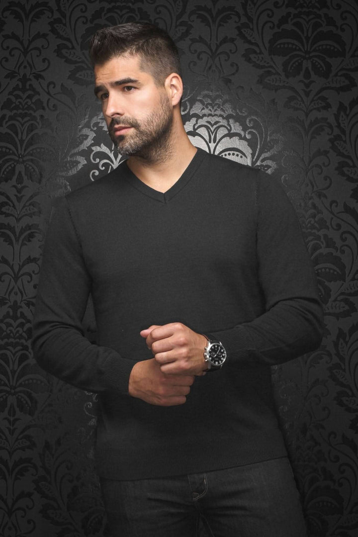Homme portant un chandail col en V en mérino noir, style élégant sur fond noir.